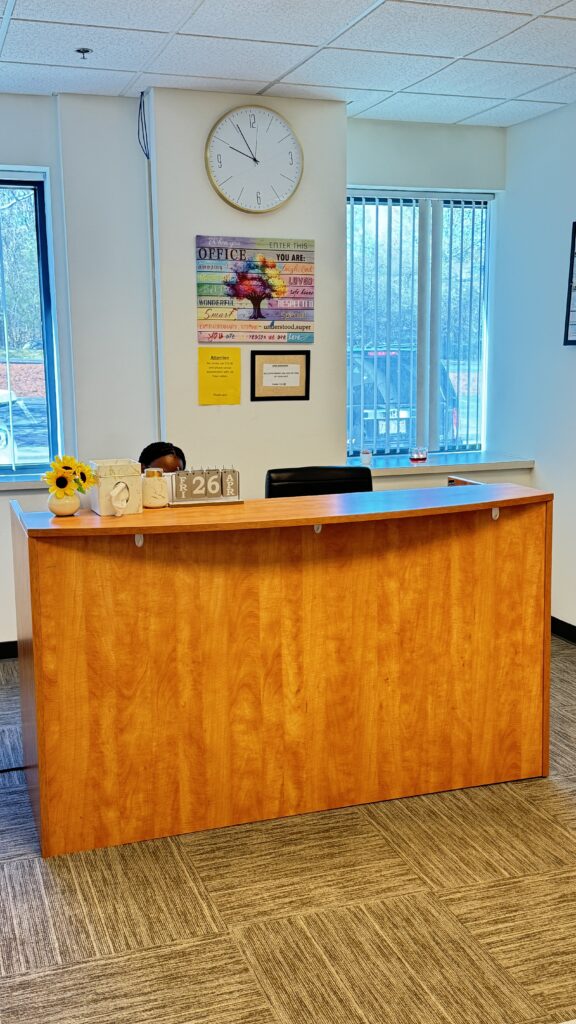 Reception desk with a flower vase and computer in a bright office space.